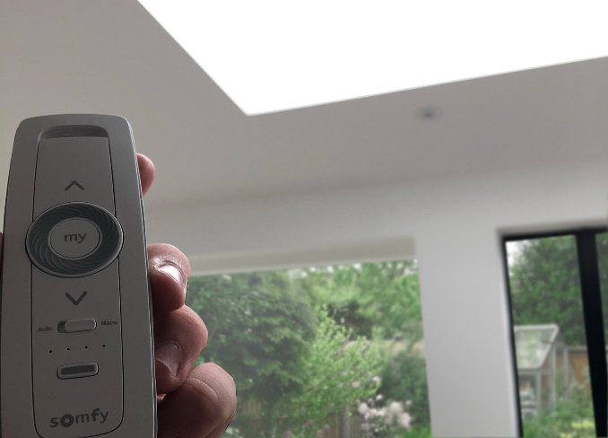 Someone Holding a Somfy Controller up to an external rooflight blind.